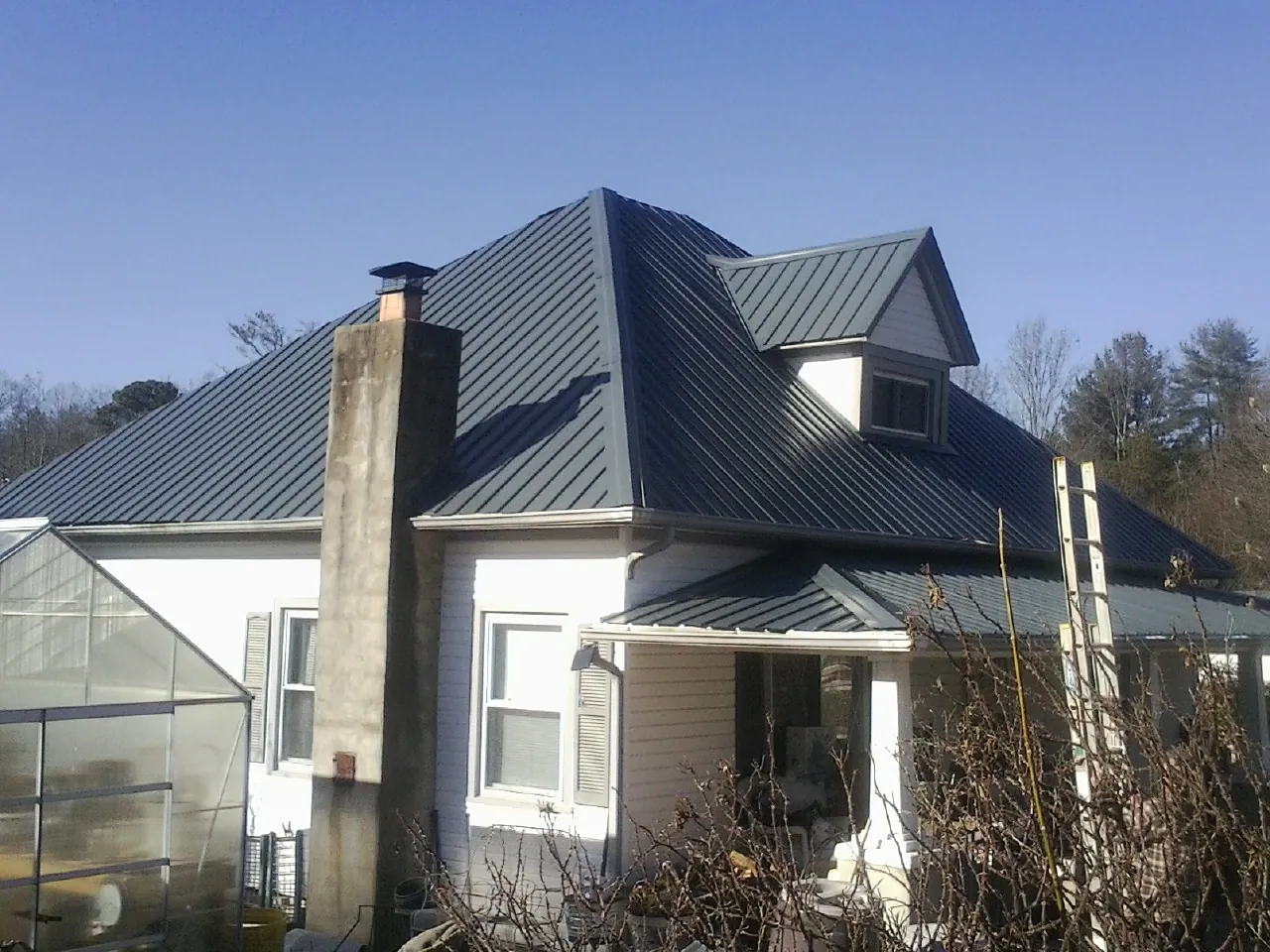 Dark blue standing seam metal roof on a white farmhouse with dormer — Slate & Tile Roof Repair by Roofing Brothers in Addy