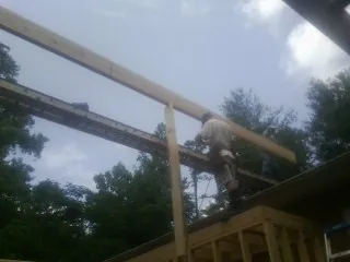 Carpenter setting a ridge beam over a new addition frame — Ice Dam Removal by Roofing Brothers in Addy