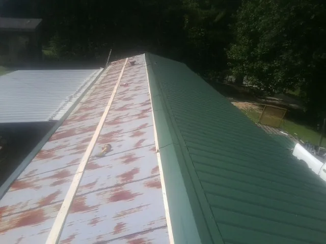 Old rusted panels beside newly installed green metal roofing — Wind Damage Roof Repair by Roofing Brothers in Addy