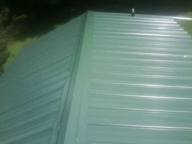 New green metal panels meeting at the ridge of a roof — Flat Roof Repair work by our crew in Addy