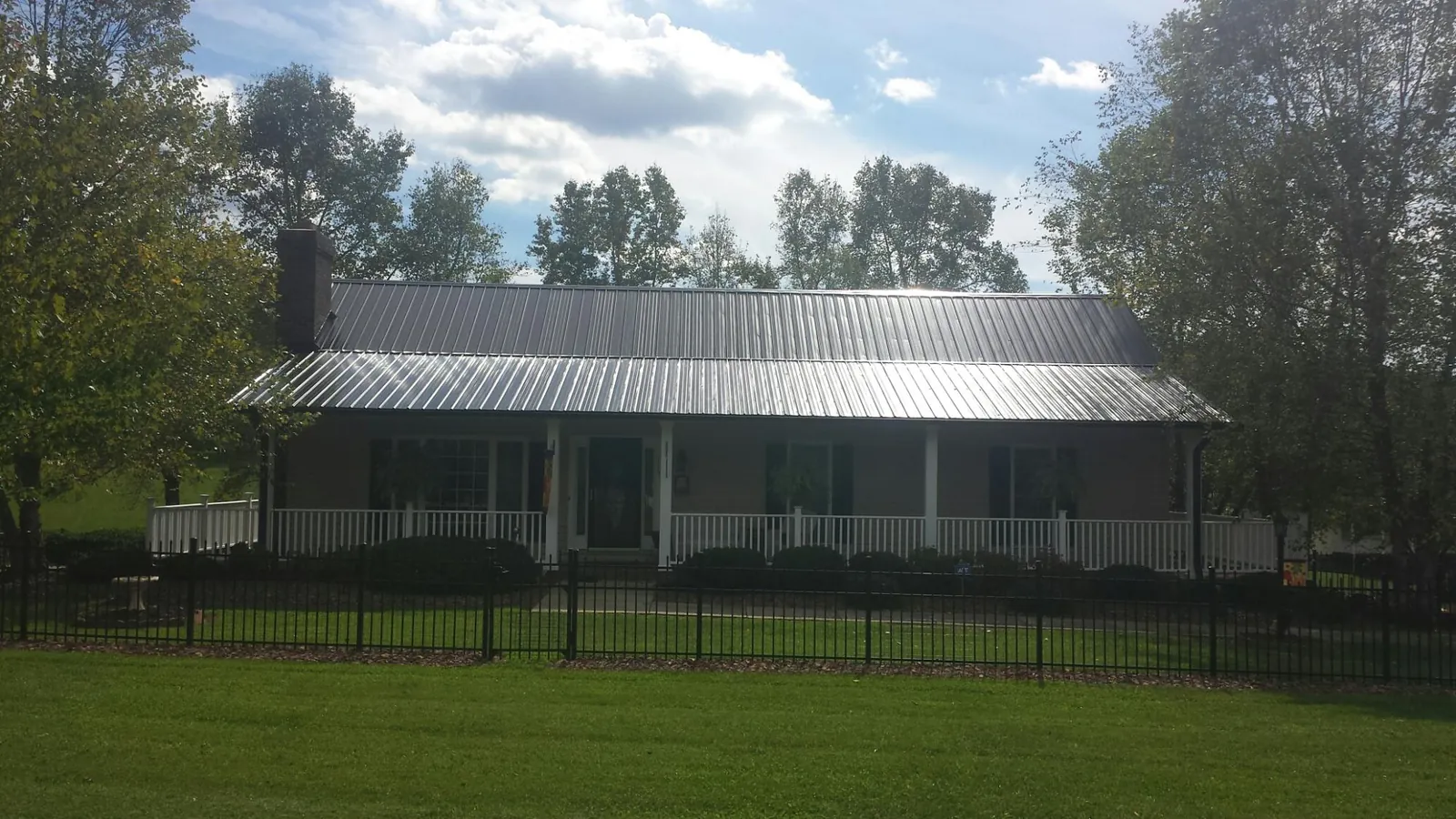 Gray metal roof on a brick ranch with a full width front porch — Gutter Guard Installation work by our crew in Addy